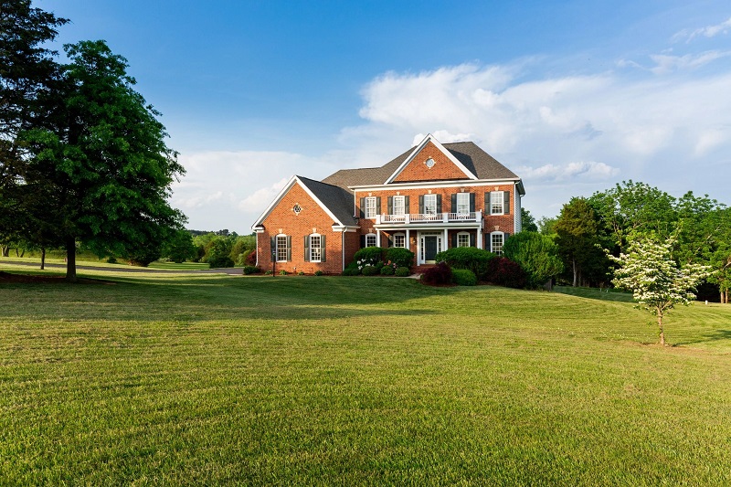 A large brick house sitting on top of a green field.